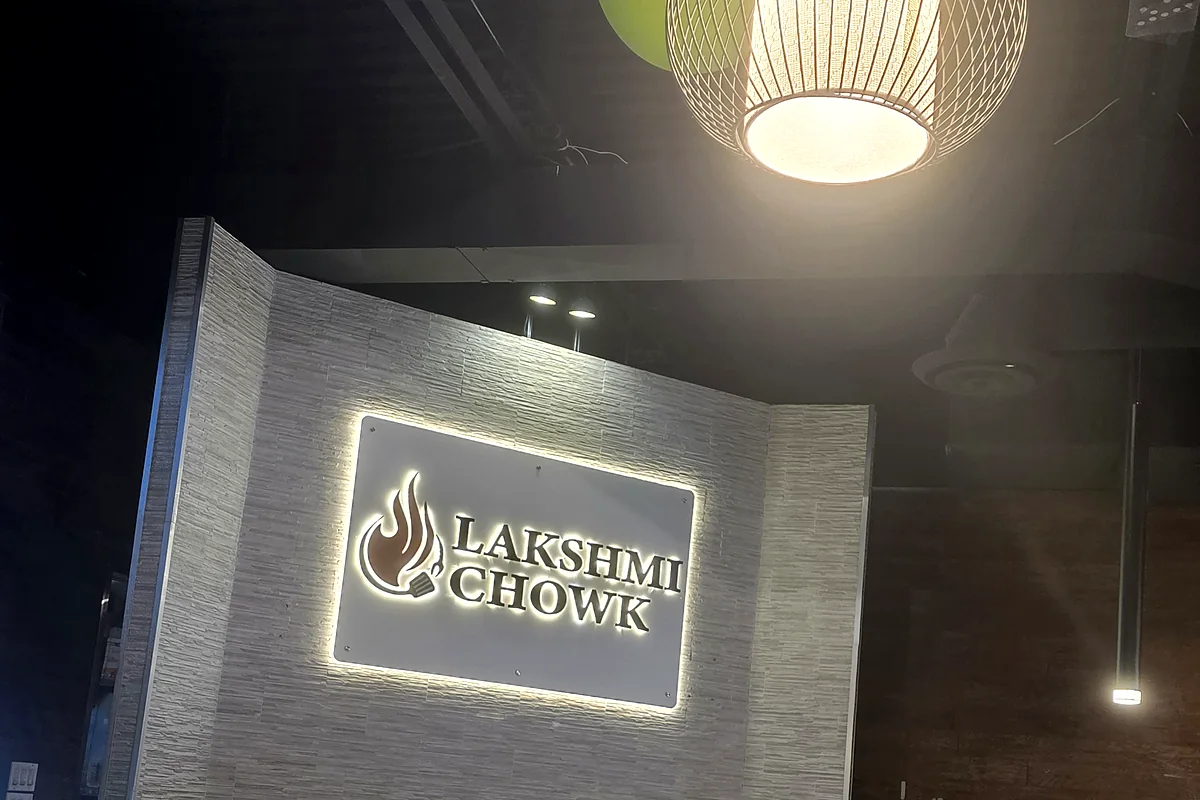 Lit Lakshmi Chowk sign on a stone feature wall above the counter