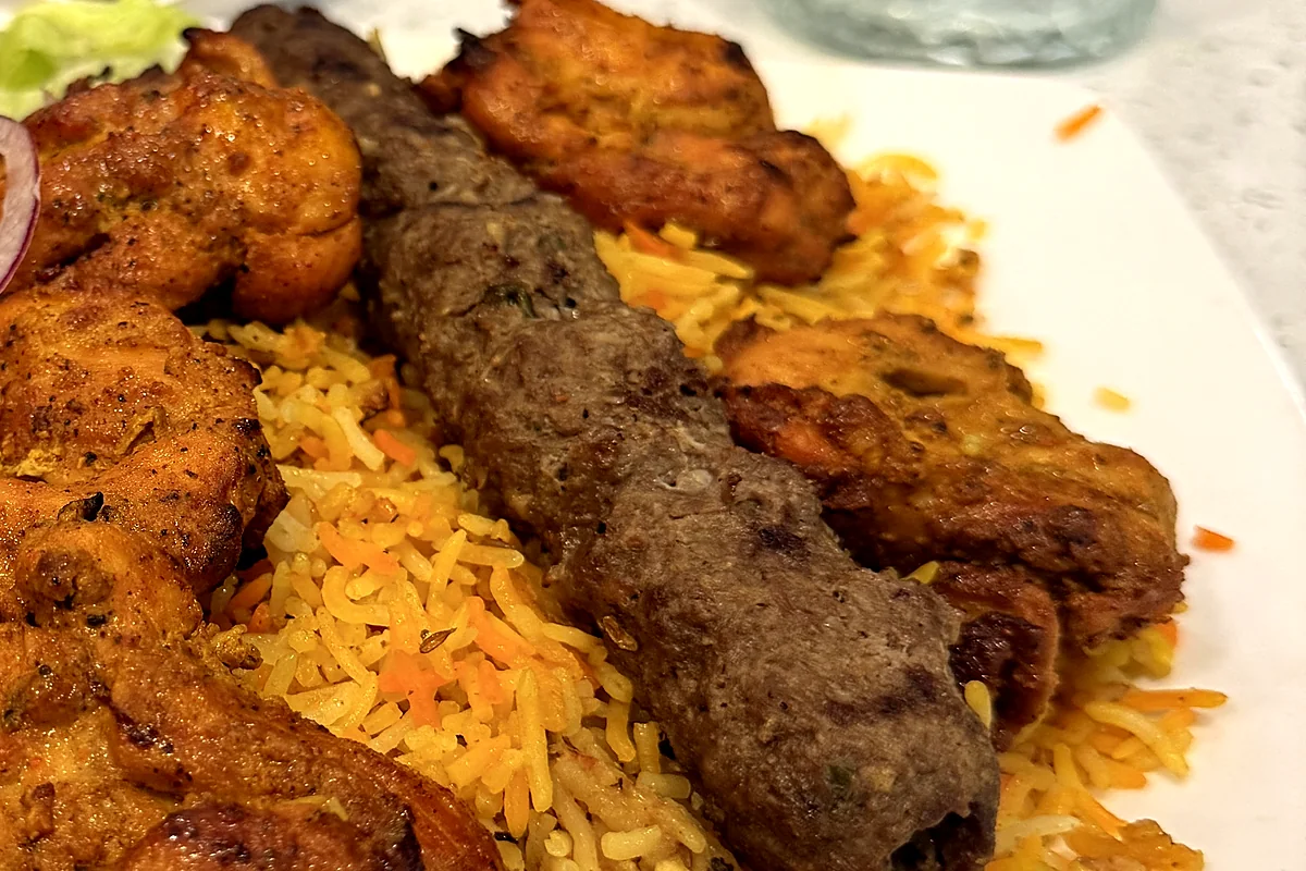 Grilled seekh kabab with fried chicken pieces on a bed of biryani rice