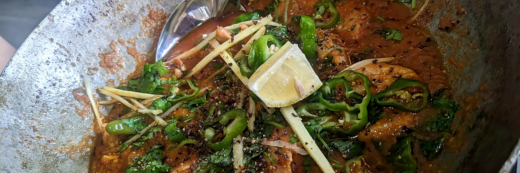 Chicken karahi with green chilies and ginger in a steel pan